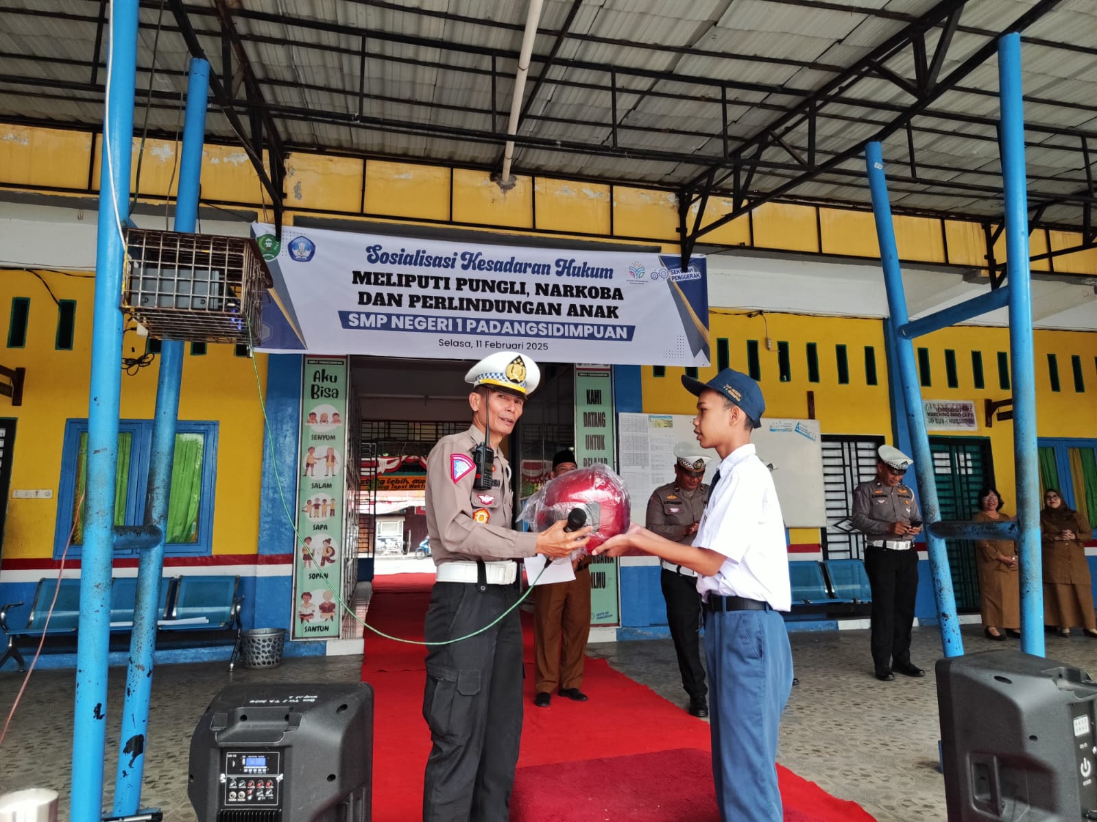 Kasat Lantas Polres Padangsidimpuan, AKP Rianto Polman Pasaribu, menyerahkan helm gratis ke salah seorang siswa SMPN 1 yang berhasil menjawab pertanyaan dengan benar