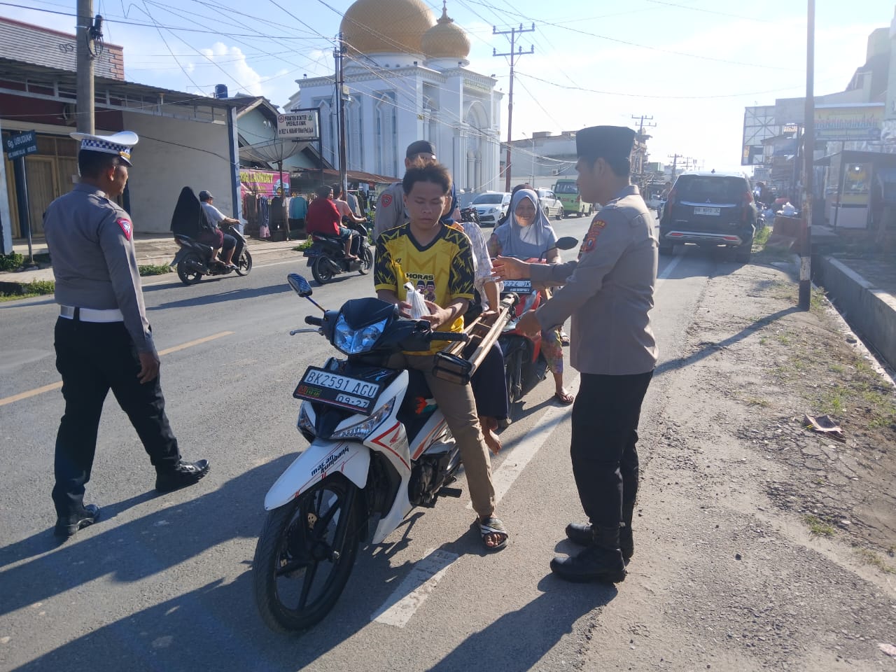 Kapolsek Padang Bolak, AKP Muallim Harahap, membagikan takjil ke pengendara yang melintas