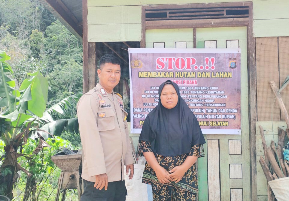 Bhabinkamtibmas Polsek Dolok, Bripka Impong Harahap, saat bertatap muka dengan warga binaan sambil memasang spanduk bertajuk, 'Stop Karhutla' di Desa Silogo-logo