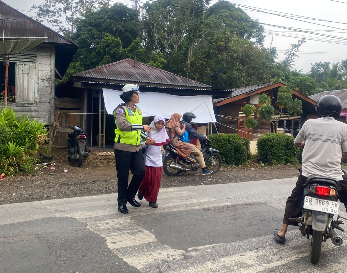Kanit Kamsel Sat Lantas Polres Tapsel, Aiptu Kasianna Saragih, saat melaksanakan tugas pengaturan arus lalulintas sembari menyeberangkan siswa SD Negeri 1 Pargarutan