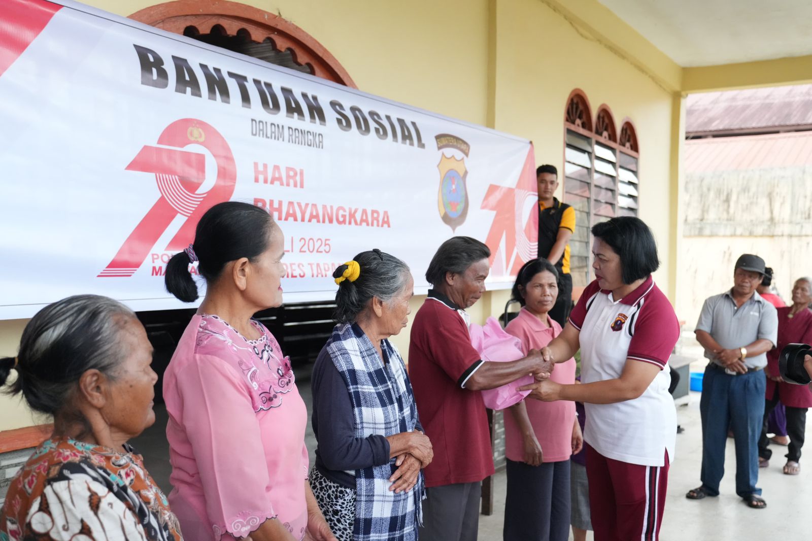 Kasi Humas Polres Tapsel, AKP Maria Marpaung, saat menyerahkan paket sembako ke para warga penerima manfaat dalam rangka menyambut HUT Bhayangkara ke-79
