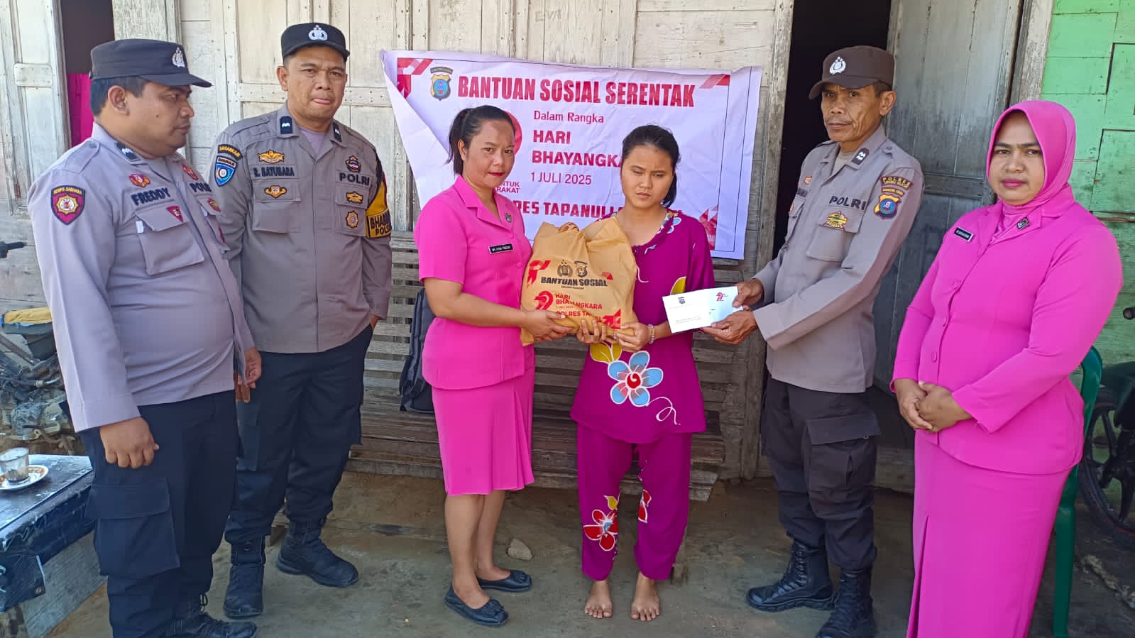 Personel Polsek SD Hole bersama pengurus Bhayangkari ranting setempat saat menyerahkan bantuan paket sembako ke warga dalam rangka menyambut HUT Bhayangkara ke-79