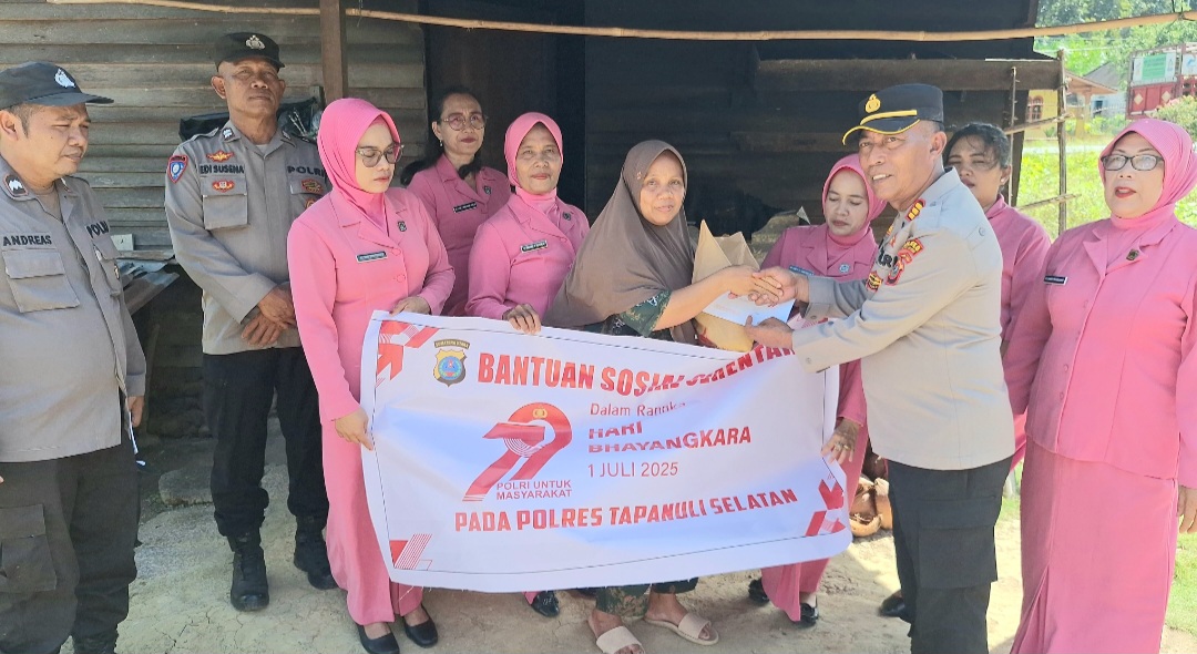 Kapolsek Batang Angkola, AKP R Trihardjanto, saat menyerahkan paket bansos ke salah satu warga dalam rangka menyambut HUT Bhayangkara ke-79