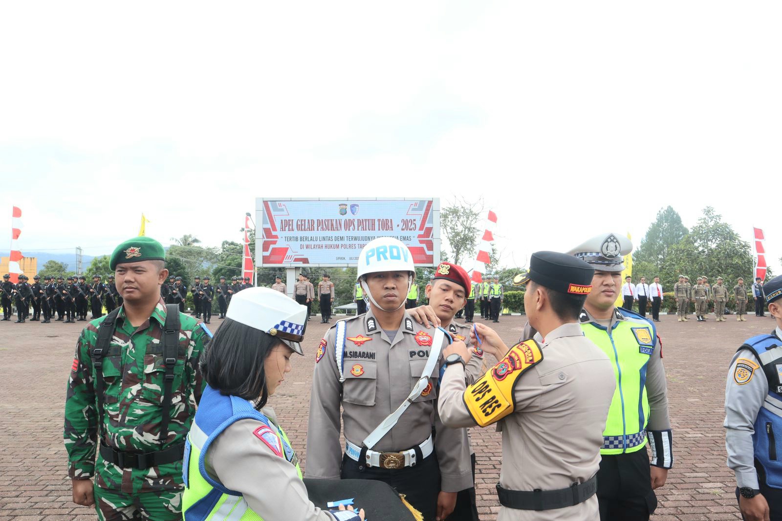 Waka Polres Tapsel, Kompol Rapi Pinakri, saat menyematkan pita tanda Operasi dalam Apel Gelar Pasukan Operasi Patuh Toba 2025