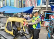 Personel Polantas Polres Padangsidimpuan terlihat tersenyum hangat saat menyerahkan bendera merah putih ke pengendara becak bermotor di Jalan Sudirman