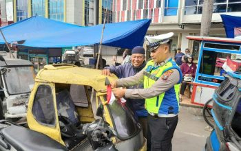 Personel Polantas Polres Padangsidimpuan terlihat tersenyum hangat saat menyerahkan bendera merah putih ke pengendara becak bermotor di Jalan Sudirman