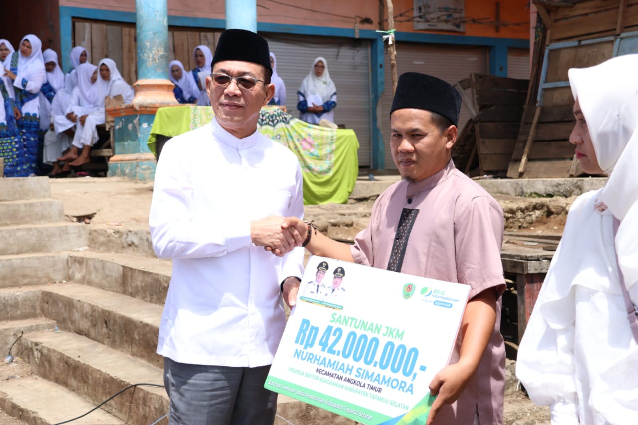 Bupati Tapsel, Gus Irawan Pasaribu, menyerahkan JKM BPJS Ketenagakerjaan ke penerima manfaat saat menghadiri peringatan Maulid Nabi Muhammad SAW yang dirangkai dengan pengajian Pemerintah Kecamatan dan BKMT Angkola Timur