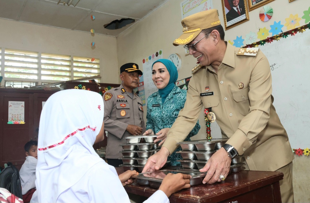 Bupati Tapsel, Gus Irawan Pasaribu, bersama Ketua TP PKK Ny Murni Gus Irawan, menyajikan langsung sajian makanan bergizi ke salah satu siswa di sela peninjauan pelaksanaan perdana program MBG di SD Negeri 101216 Situmba