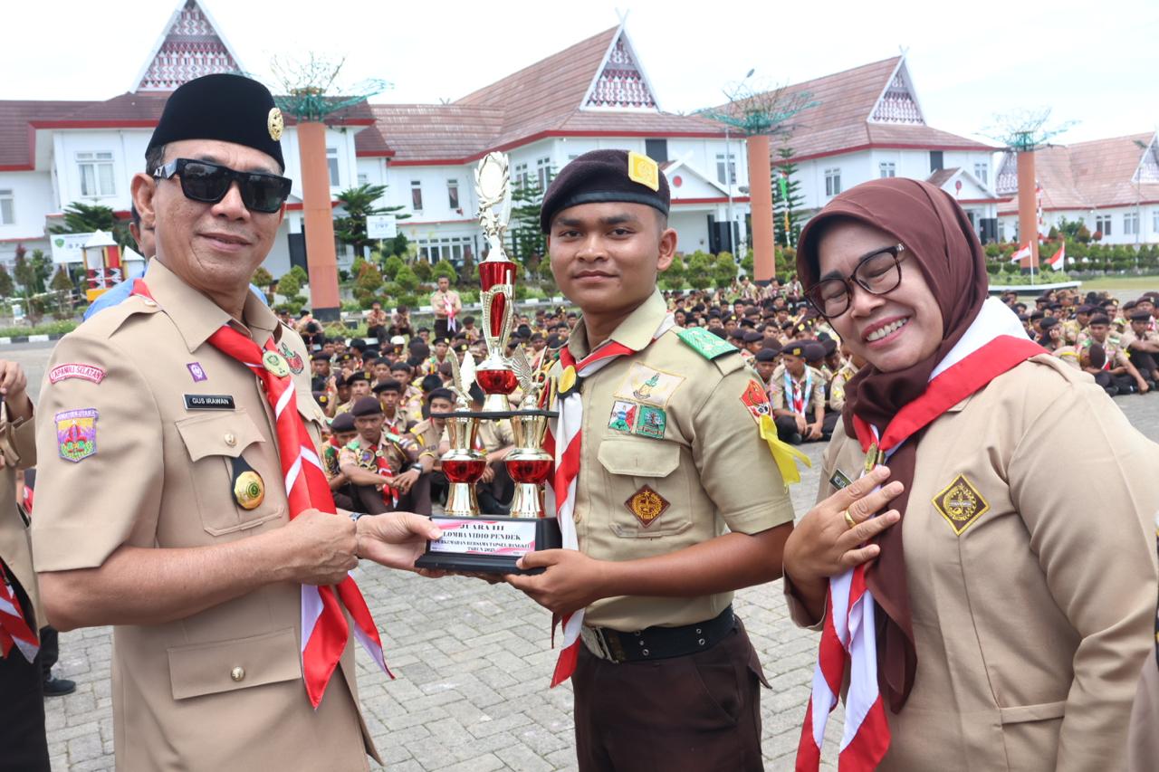 Bupati Tapsel, Gus Irawan Pasaribu, saat menyerahkan trofi ke perwakilan SMK N 1 Batang Angkola yang keluar sebagai juara ketiga lomba vidio pendek dalam agend Perkemahan Bersama 'Tapsel Bangkit' 2025